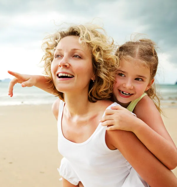 A mother and daughter laughing together on a beach